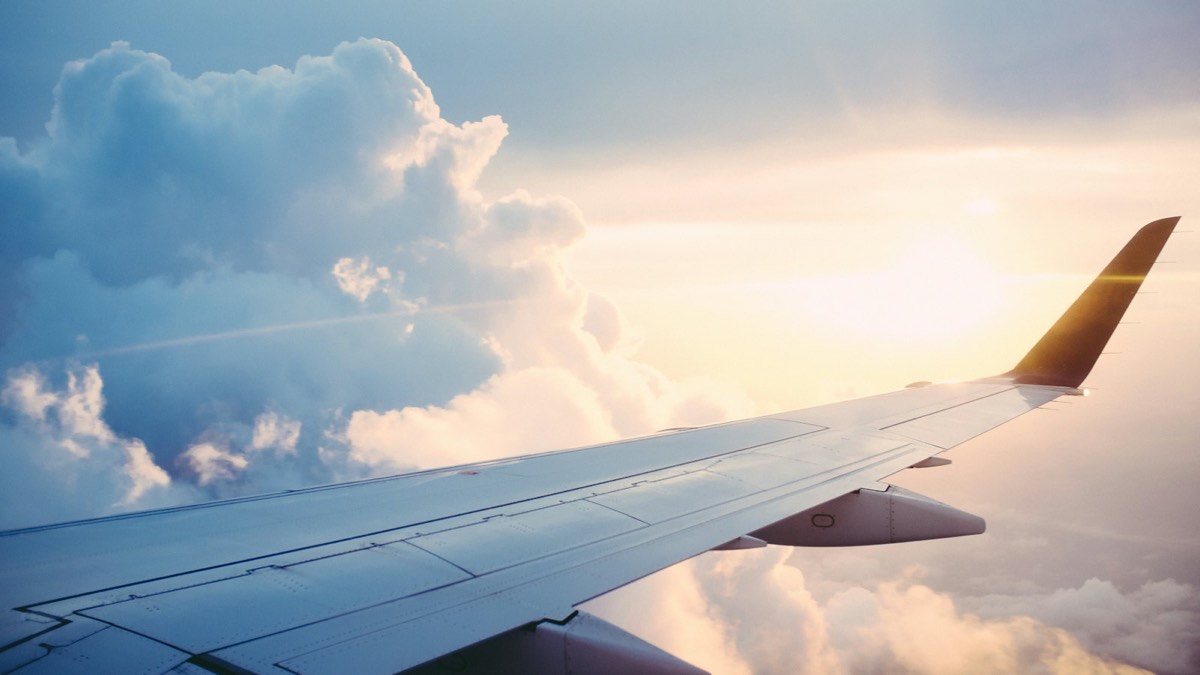 Airplane wing above the clouds at sunrise
