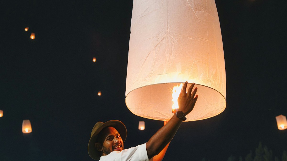 Traveller releasing a glowing sky lantern at night