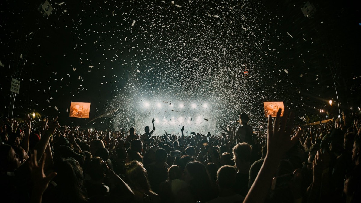 Festival crowd under stage lights and confetti at night