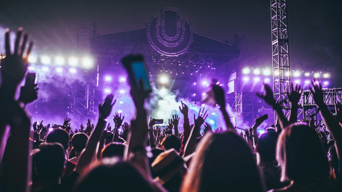 Festival crowd raising their hands in front of a lit stage
