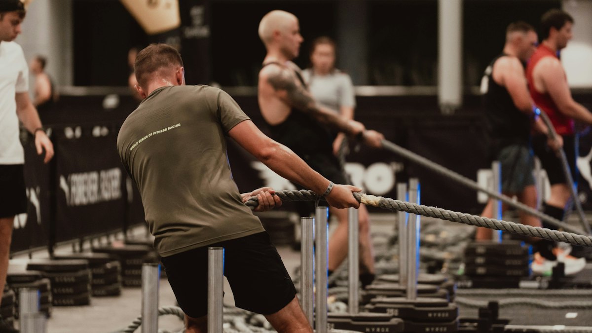 Athlete pulling a weighted sled with a rope at a HYROX-style training session