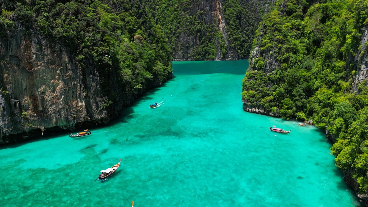 Longtail boats in a turquoise lagoon surrounded by limestone cliffs