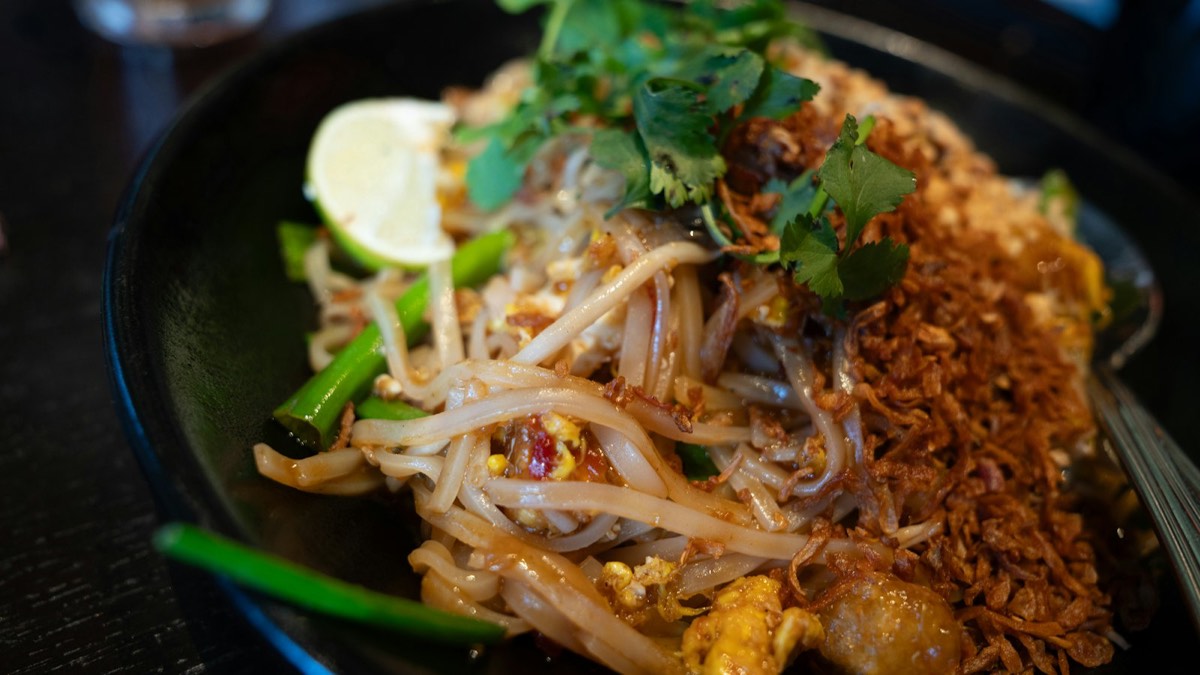 Plate of pad Thai noodles with fresh herbs and lime